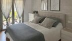 Dormitorio luminoso con cama doble, colcha gris, pared de ladrillo y acceso a balcón en Palma de Mallorca