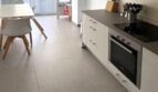 Sala de estar-comedor moderna con cocina empotrada blanca, placa de cocción, horno y suelo de baldosas claras en Palma