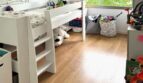 Habitación infantil con cama alta, suelo de madera, almacenamiento de juguetes y gran ventana con vistas al verde en Palma