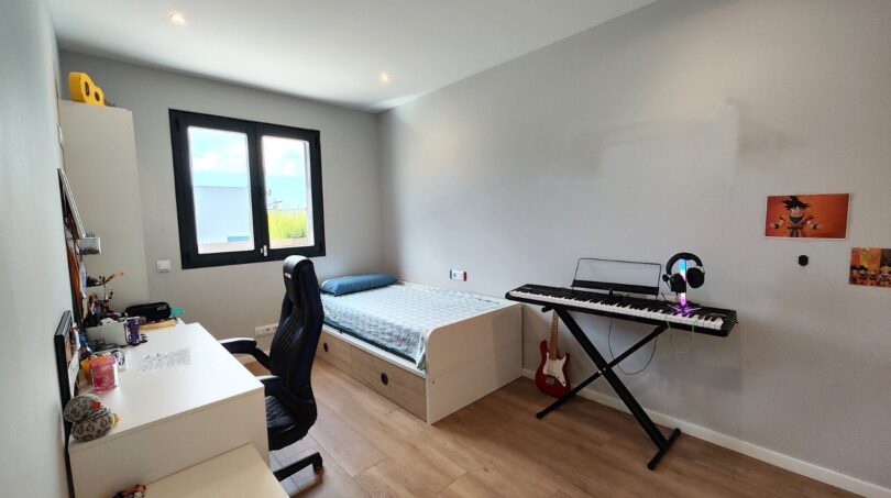 Jugendzimmer mit Schreibtisch, Gaming-Stuhl, Einzelbett, E-Gitarre und Keyboard im modernen Einfamilienhaus Marratxí.