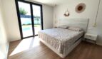 Helles Schlafzimmer mit Doppelbett, Holzboden und Glastür zum Pool in modernem Einfamilienhaus in Marratxí