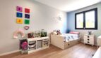 Kinderzimmer mit Holzboden, bunten Wanddekos, Stauregal und Einzelbett im modernen Einfamilienhaus Marratxí.