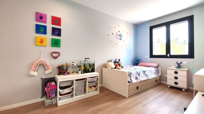 Kinderzimmer mit Holzboden, bunten Wanddekos, Stauregal und Einzelbett im modernen Einfamilienhaus Marratxí.