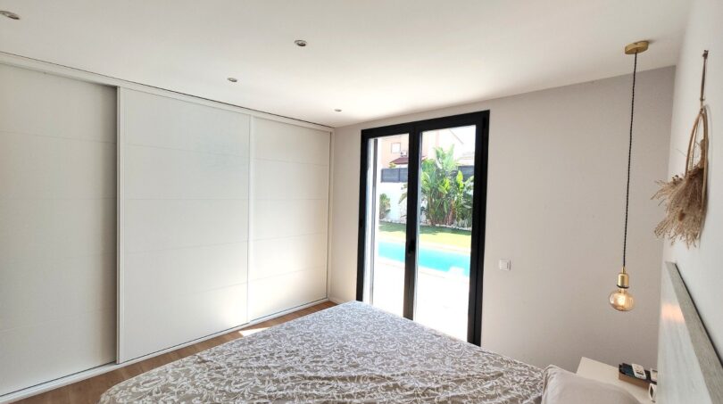 Helles Schlafzimmer mit Einbauschrank und Glastür zum privaten Pool in modernem Einfamilienhaus in Marratxí