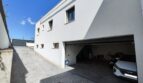 Geräumige Garage mit Hyundai und Motorrad, gepflasterter Einfahrt und weißer Fassade des modernen Einfamilienhauses in Marratxí.