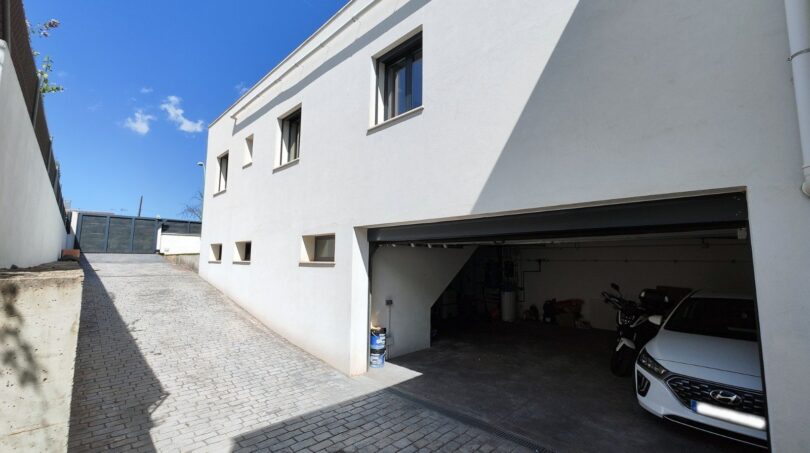 Geräumige Garage mit Hyundai und Motorrad, gepflasterter Einfahrt und weißer Fassade des modernen Einfamilienhauses in Marratxí.