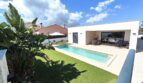 Modernes Einfamilienhaus in Marratxí mit rechteckigem Pool, Terrasse und tropischen Pflanzen unter blauem Himmel.