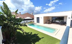 Modern single-family house in Marratxí with rectangular pool, terrace and tropical plants under blue sky.