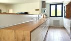 Moderne Küche mit Holzarbeitsplatte, weißen Fronten und großem Fenster im Einfamilienhaus Marratxí