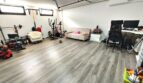 Multifunktionaler Kellerraum mit Heimtrainer, Fitnessgeräten, Arbeitsbereich und Holzlaminatboden in Marratxí.