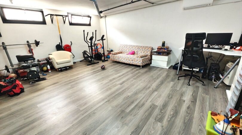 Multifunktionaler Kellerraum mit Heimtrainer, Fitnessgeräten, Arbeitsbereich und Holzlaminatboden in Marratxí.