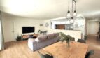 Offener Wohn-Essbereich mit Holztisch, grauem Sofa, TV-Wand und moderner Pendelleuchten in Marratxí