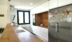Moderne Küche mit Holztheke, weißen Hochglanzschränken und Edelstahl-Kühlschrank im Einfamilienhaus Marratxí