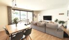 Helles Wohn-Esszimmer mit grauem Sofa, Holztisch, TV und Zugang zur Terrasse in modernem Einfamilienhaus Marratxí