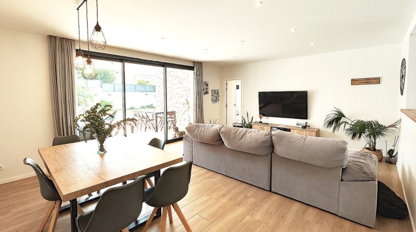 Helles Wohn-Esszimmer mit grauem Sofa, Holztisch, TV und Zugang zur Terrasse in modernem Einfamilienhaus Marratxí