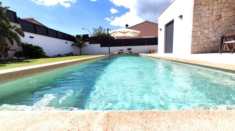 Privater Pool mit türkisblauem Wasser, Liegestühlen und Sonnenschirm im gepflegten Garten eines modernen Einfamilienhauses in Marratxí.