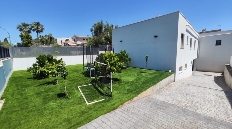 Gepflegter Garten mit Kunstrasen, Obstbäumen und Spielbereich neben modernem Wohnhaus in Marratxí