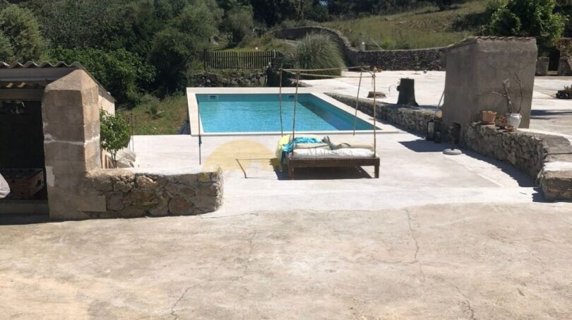 Rustikale Finca in Artà: Natursteinterrasse mit Pool, Hängebett und Blick auf grüne Hügel