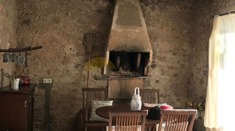 Überdachte Terrasse der Finca Artà mit rustikalem Grillkamin, Natursteinwänden und Holzmöbeln