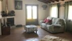Rustikales Wohnzimmer der Finca in Artà mit Holzbalkendecke, Kamin und Natursteinboden
