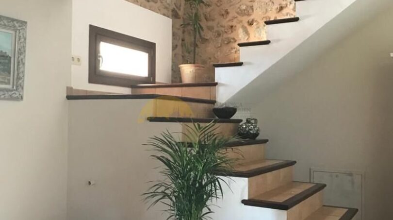 Rustikale Treppe mit Holzstufen und Natursteinwand in einer Finca in Artà, Mallorca