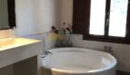 Luxuriöses Badezimmer der Finca in Artà mit runder Einbaubadewanne, Holzbalkendecke und Natursteinwaschbecken