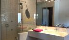 Modernes Badezimmer der Finca Artà mit Glasdusche, weißem Waschtisch und Holzbalkendecke