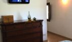 Schlafzimmer der Finca Artà mit Holzbalkendecke, antikem Kommode, WandTV und blauer Tagesdecke