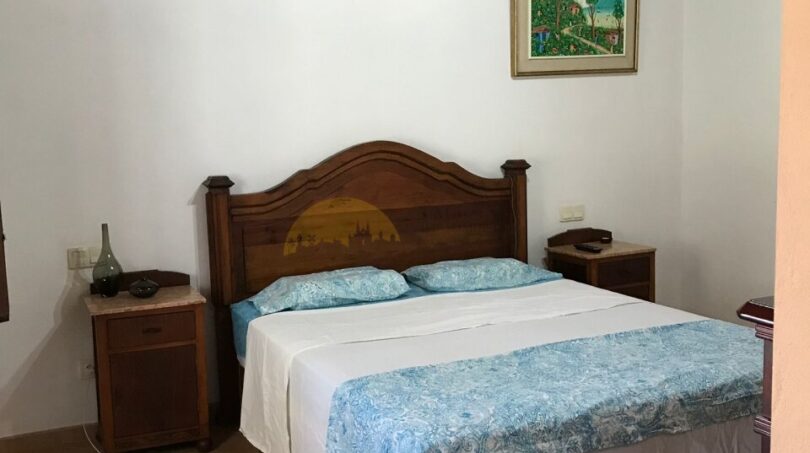 Gemütliches Schlafzimmer der Finca Artà mit Holzbalkendecke, Doppelbett und rustikalem Holzmobiliar.