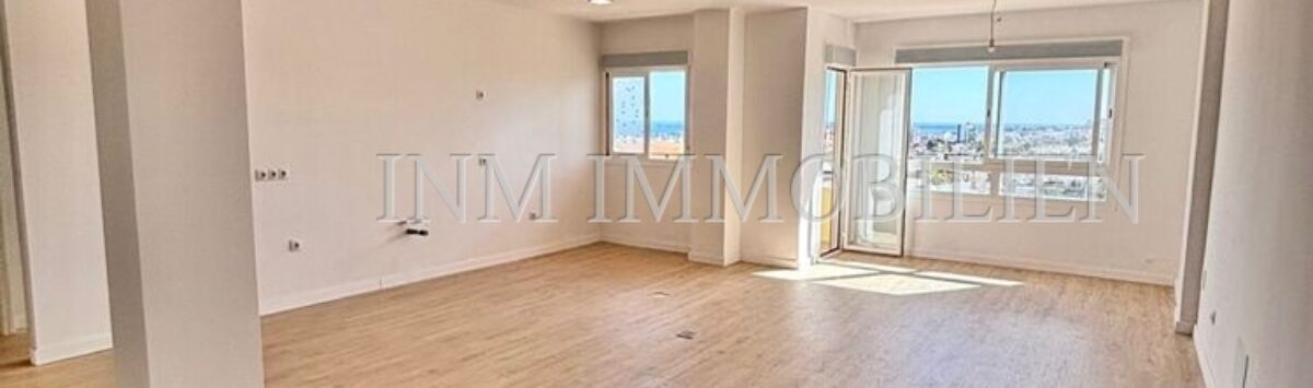 Luminoso salón vacío con suelo de parquet y grandes ventanales con vistas a la ciudad en apartamento renovado, Palma