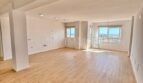 Luminoso salón vacío con suelo de parquet y grandes ventanales con vistas a la ciudad en apartamento renovado, Palma