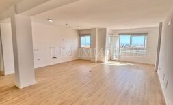 Helles, leeres Wohnzimmer mit Parkettboden und großen Fenstern mit Stadtblick in renovierter Wohnung, Palma