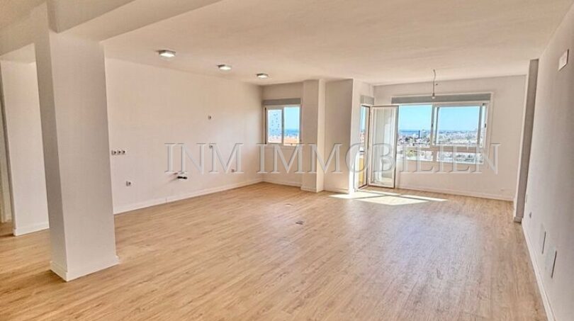 Bright, empty living room with parquet flooring and large windows with city view in renovated apartment, Palma