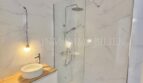 Modernes Badezimmer mit Marmoroptik-Fliesen, Glasdusche und Holz-Waschtisch in renovierter Wohnung, Palma