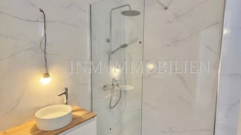 Modernes Badezimmer mit Marmoroptik-Fliesen, Glasdusche und Holz-Waschtisch in renovierter Wohnung, Palma
