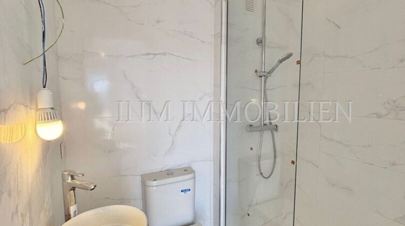 Modernes Bad mit Marmorfliesen, Walk-in-Dusche, WC und Waschtisch auf Holzunterschrank in Palma.