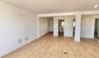 Helles, leeres Wohnzimmer mit hellem Laminatboden und weißen Wänden in renovierter Wohnung in Son Espanyolet