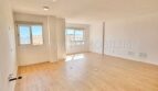 Helles, leeres Wohnzimmer mit Laminatboden und großen Fenstern in renovierter Wohnung in Son Espanyolet, Palma