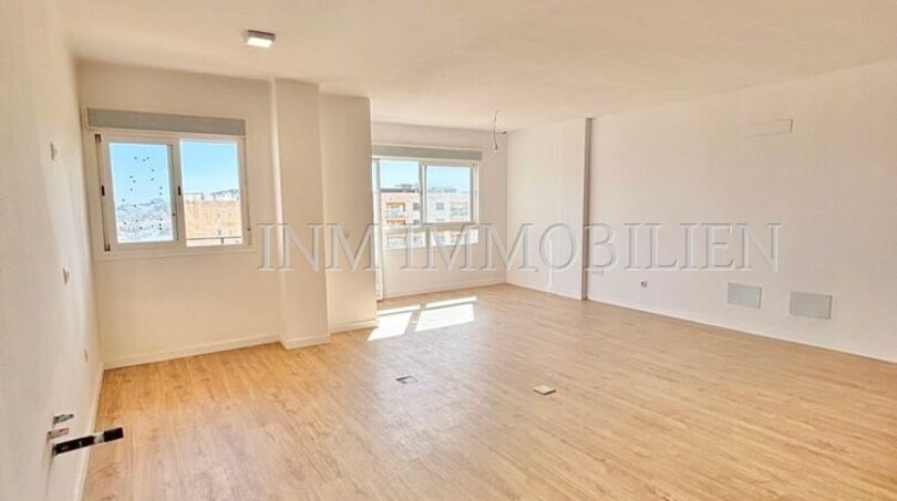 Helles, leeres Wohnzimmer mit Laminatboden und großen Fenstern in renovierter Wohnung in Son Espanyolet, Palma
