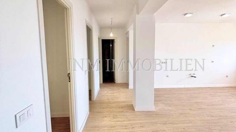 Heller, renovierter Wohnbereich mit Laminatboden, weißen Wänden und Blick in den Flur der Wohnung in Son Espanyolet.