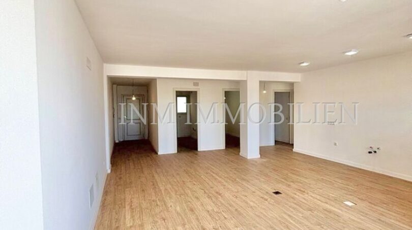 Helles, leeres Wohnzimmer mit Laminatboden und weißen Wänden in renovierter Wohnung in Son Espanyolet, Palma