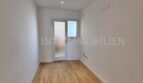 Leeres Zimmer mit Laminatboden, weißen Wänden, Einbauspot und Glastür in renovierter Wohnung, Palma de Mallorca.