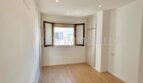 Helles, leeres Zimmer mit Laminatboden, Einbauschrank und Erkerfenster in renovierter Wohnung in Palma