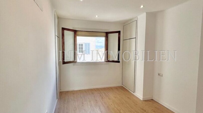 Helles, leeres Zimmer mit Laminatboden, Einbauschrank und Erkerfenster in renovierter Wohnung in Palma