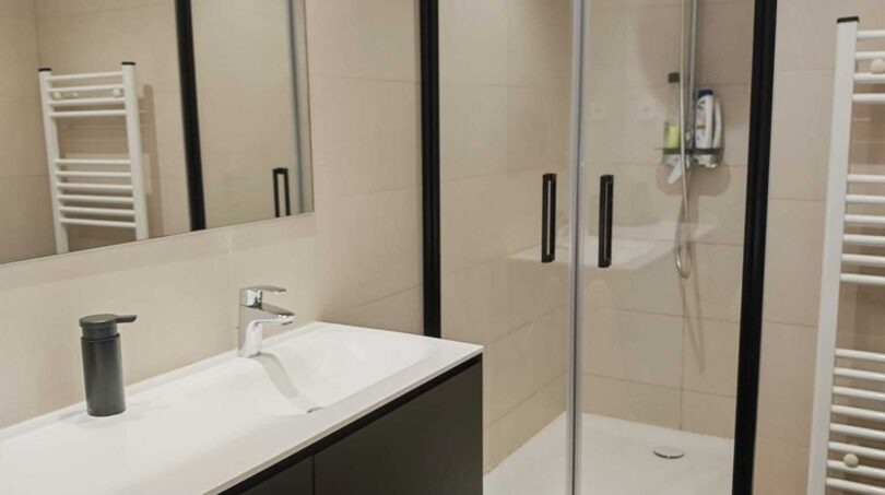 Modernes Badezimmer mit schwarzem Waschtischunterschrank, Glasdusche und weißem Heizkörper in Luxus-Apartment Palma