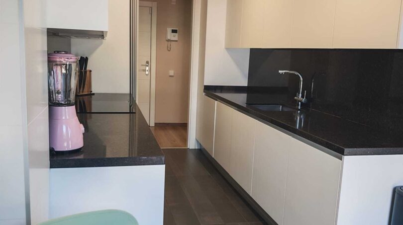 Moderne Küche mit weißen Fronten, dunkler Granitarbeitsplatte und rosa Mixer im Luxus-Apartment in Palma