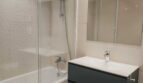 Modernes Badezimmer mit Badewanne, Glasdusche, dunkelgrauem Waschtischunterschrank und großem Spiegel im Luxus-Apartment Palma