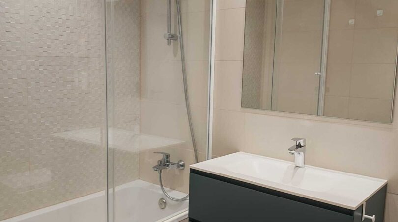 Modernes Badezimmer mit Badewanne, Glasdusche, dunkelgrauem Waschtischunterschrank und großem Spiegel im Luxus-Apartment Palma
