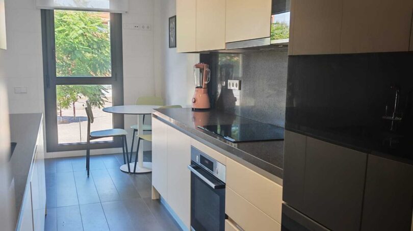 Moderne Küche mit schwarzen Arbeitsflächen, weißen Fronten und Essbereich mit Gartenblick im Luxus-Apartment Palma