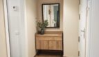 Heller Eingangsbereich mit Holzparkett, modernem Schuhschrank, Wandspiegel und Blumendekoration im Luxus-Apartment Palma